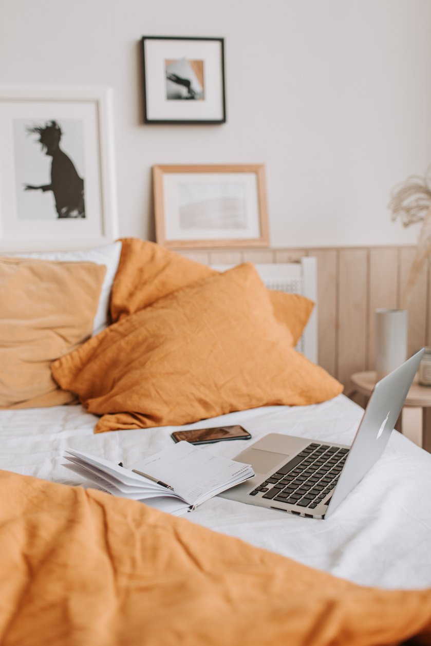 Cozy bed with laptop and notebook